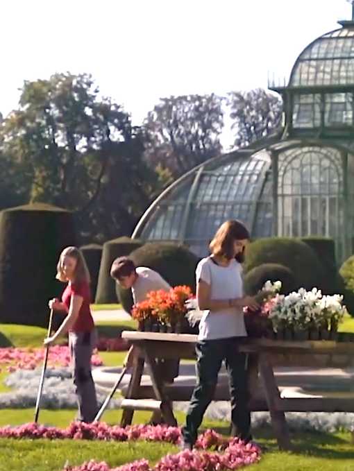 Zwei Schülerinnen und ein Schüler gärtnern vor dem Palmenhaus 