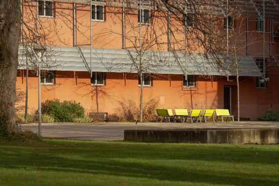 Blick auf das Schulhaus mit Gartenmöbeln