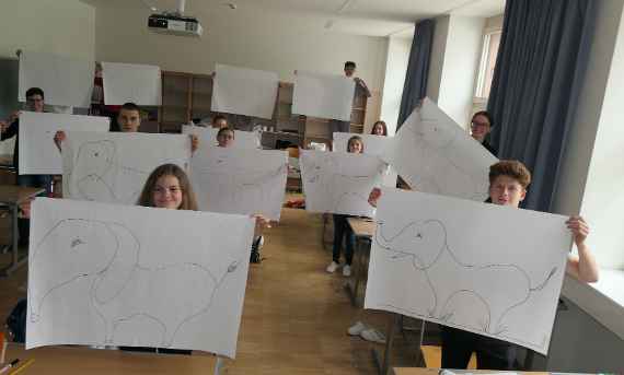 Schülerinnen und Schüler halten selbst gezeichnete Babyelefanten in die Luft