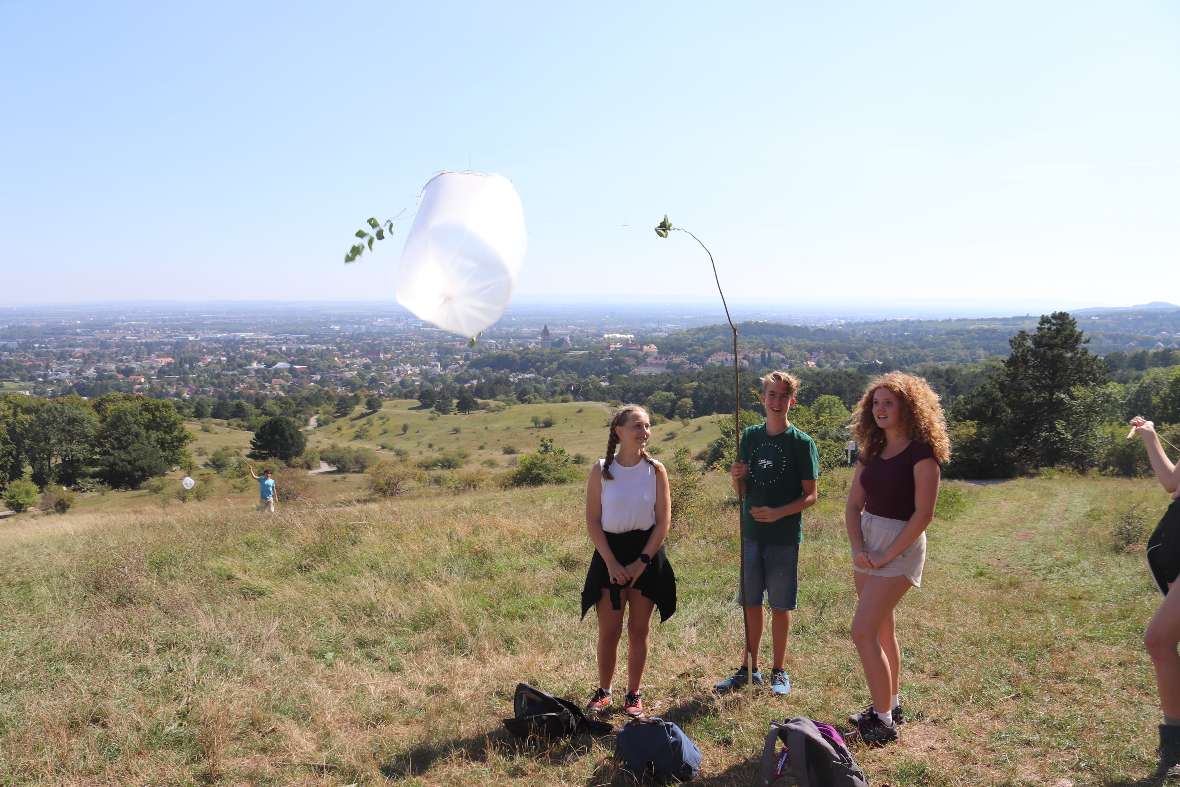 Zwei Schülerinnen und ein Schüler präsentieren ihren selbst gebastelten Flugdrachen
