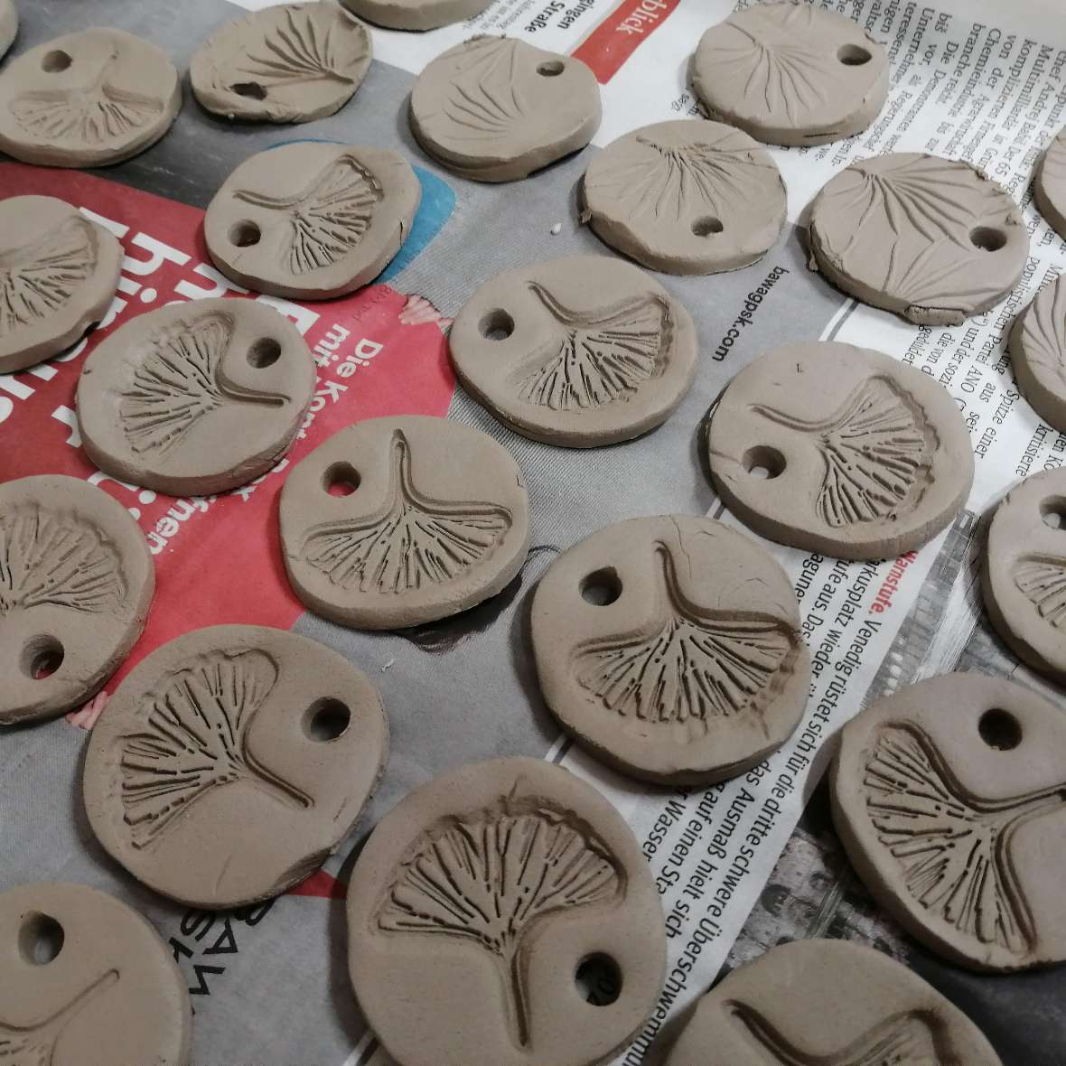 zu sehen sind rohe Ton-Medaillons die auf einem Papier liegen