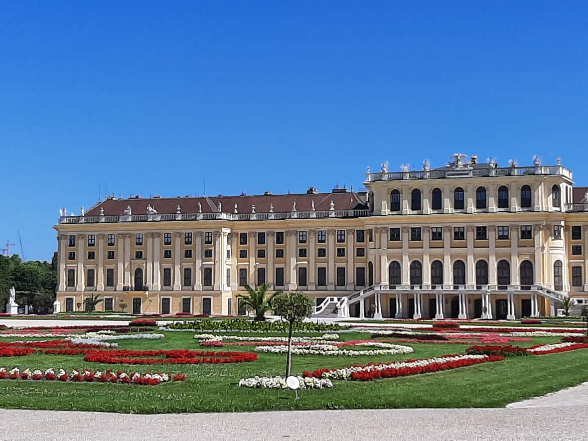 Südfassade von Schloss Schönbrunn mit Gartenparterre bei blauem Himmel 