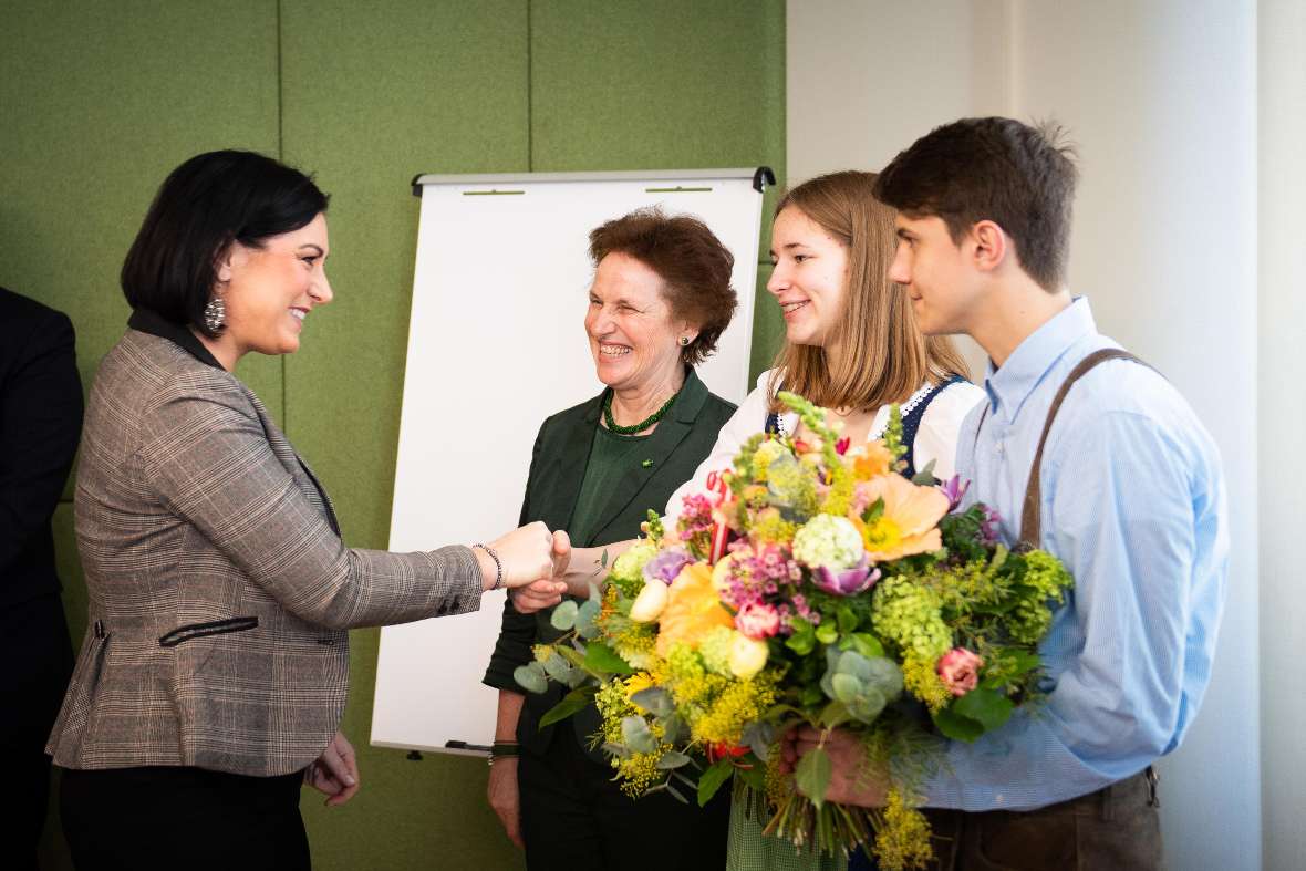 zu sehen sind 4 Personen, 2 Schüler mit Blumensträußen in der Hand