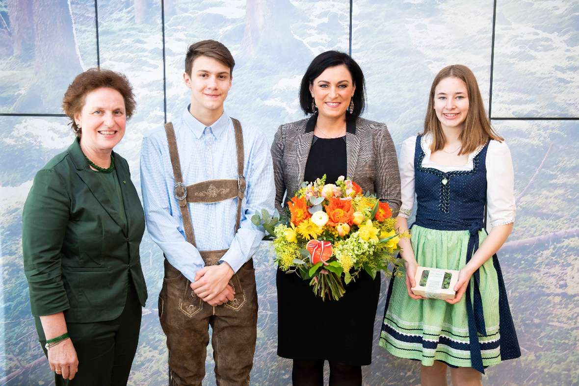 zu sehen sind vier Personen, Frau Bundesministerin Köstinger hält einen bunten Blumenstrauß in Händen