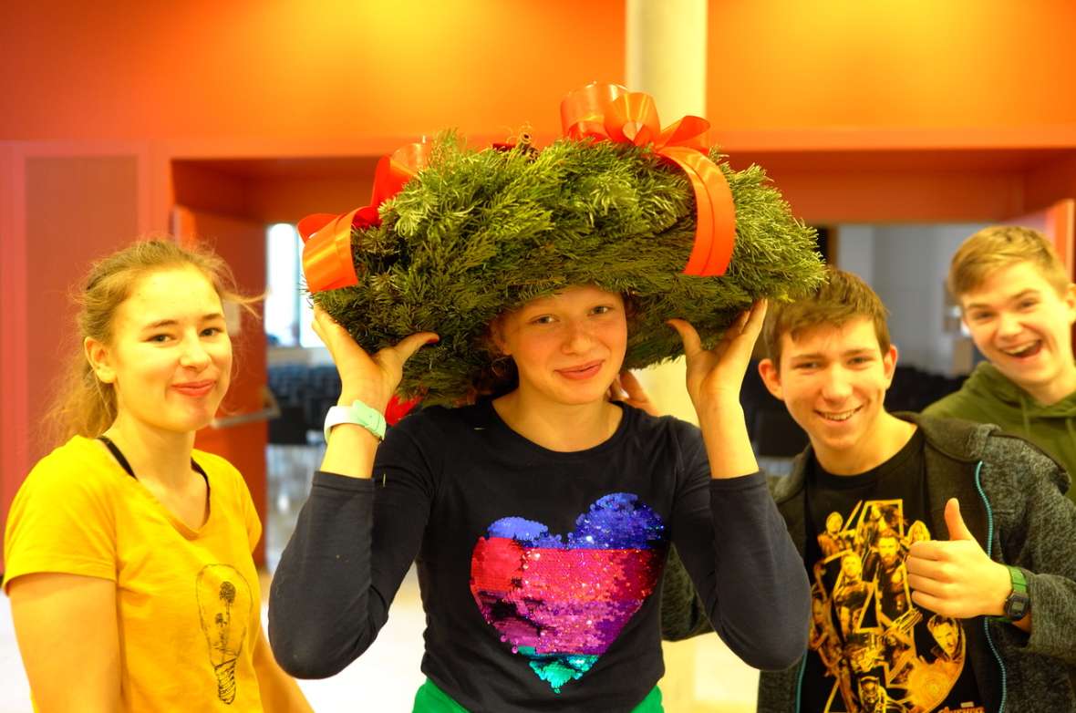 zu sehen sind drei Mädchen, das mittlere Mädchen hat einen Adventkranz auf dem Kopf