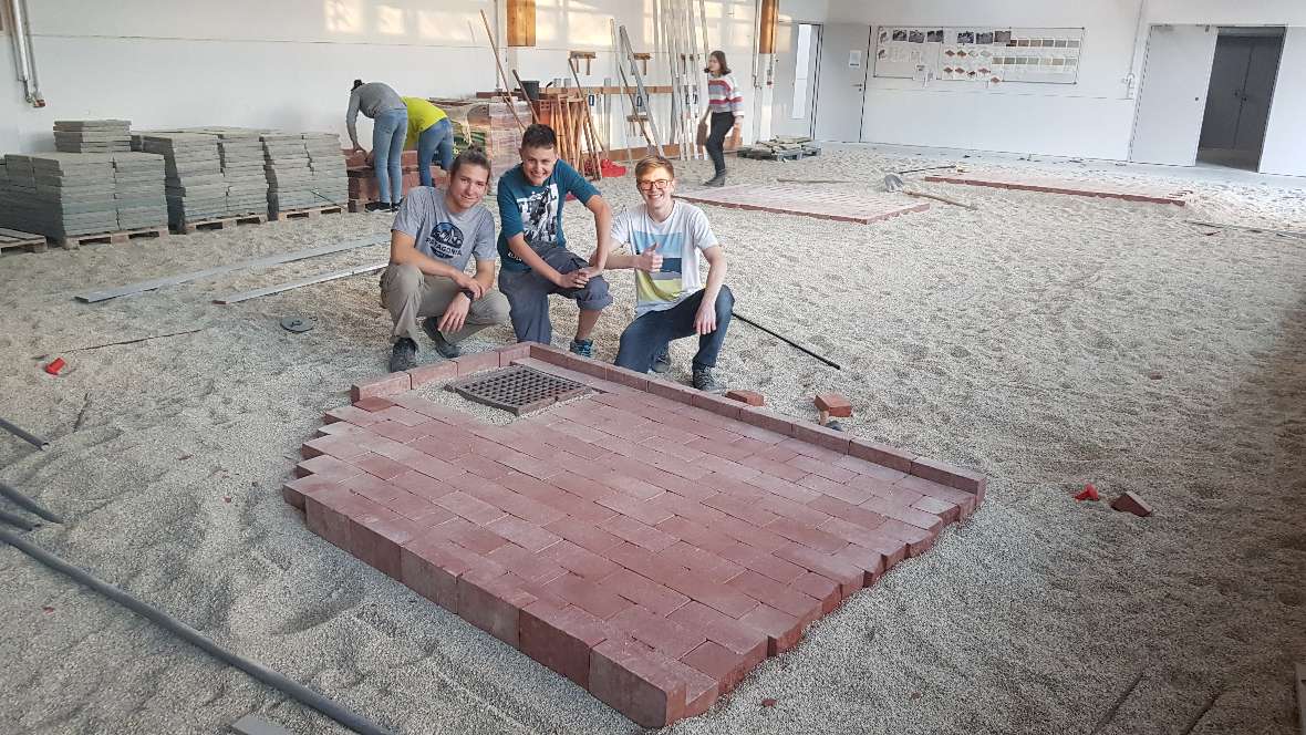 Schüler posieren vor der gepflasterten Klinkerfläche