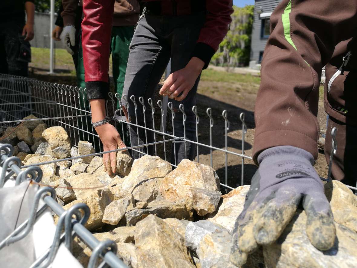 Schüler befüllen die Drahtkörbe mit Grobschlag