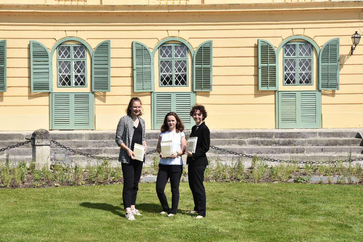 Drei Schülerinnen stehen vor dem Schloss Esterhazy in einer Grünfläche