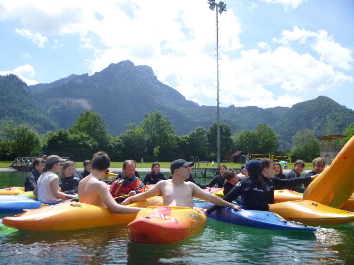 Schülerinnen und Schüler sitzen in Kajaks im Wasser