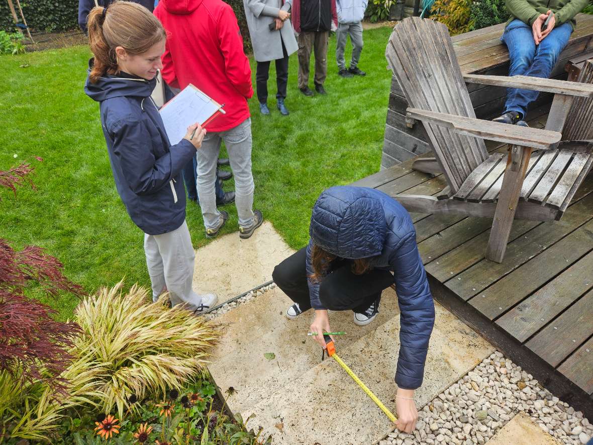 Eine Schülerin misst eine Stufe im Garten