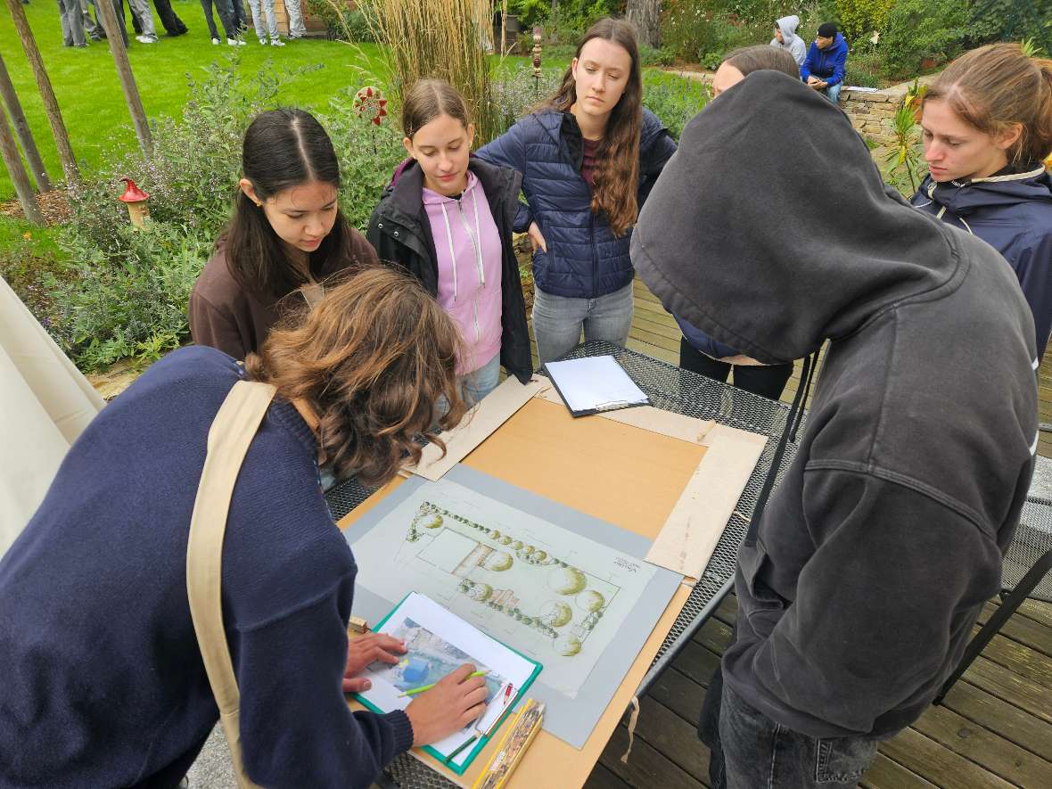 Schülerinnen und Schüler betrachten einen Gartenplan
