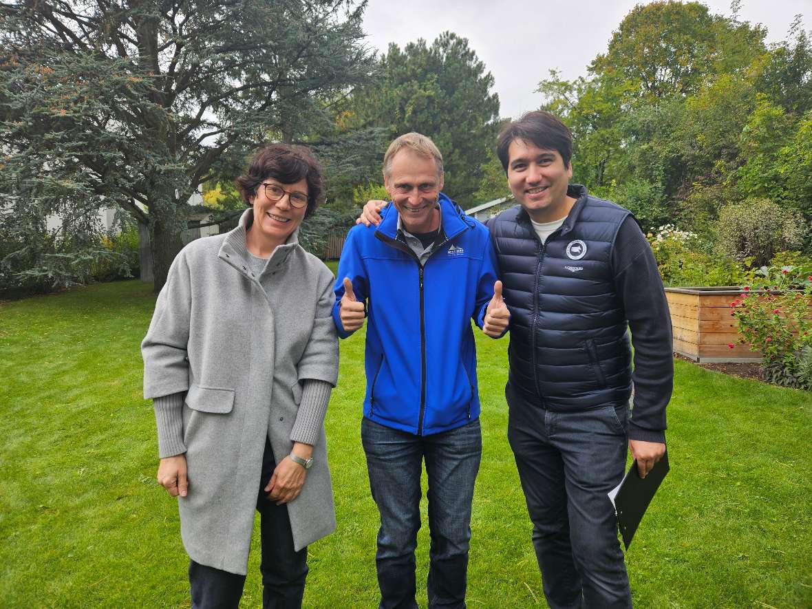 Drei Personen posieren vor einem Garten