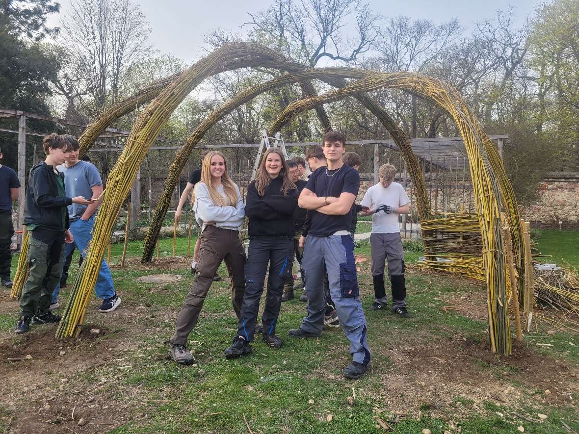Schüler*innen stehen vor Weidenpavillon. Weidenpavillon im Hintergrund.
