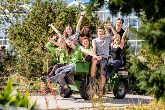 Schülerinnen und Schüler der Schule auf einem Traktoranhänger vor dem Glashaus