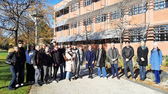 Eine Gruppe an Schüler:innen und Lehrer:innen, sowie Personen aus der Verwaltung stehen vor dem Schulgebäude