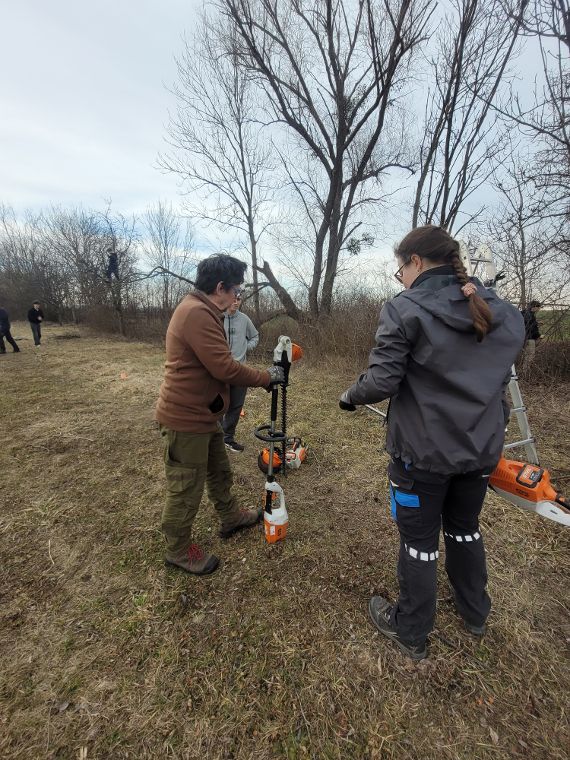 Lehrer zeigt Schülerin wie eine elektrische Heckenschere funktioniert